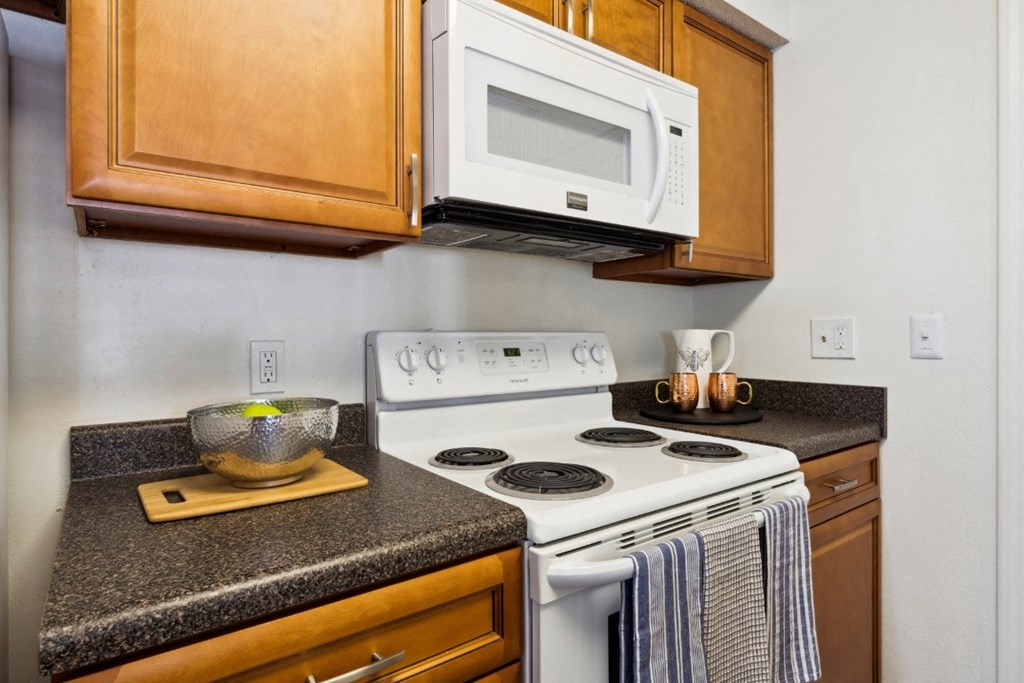 a kitchen with a white stove top oven next to a counter top with a bowl on it  at Willow Ridge Apartments, Charlotte, North Carolina