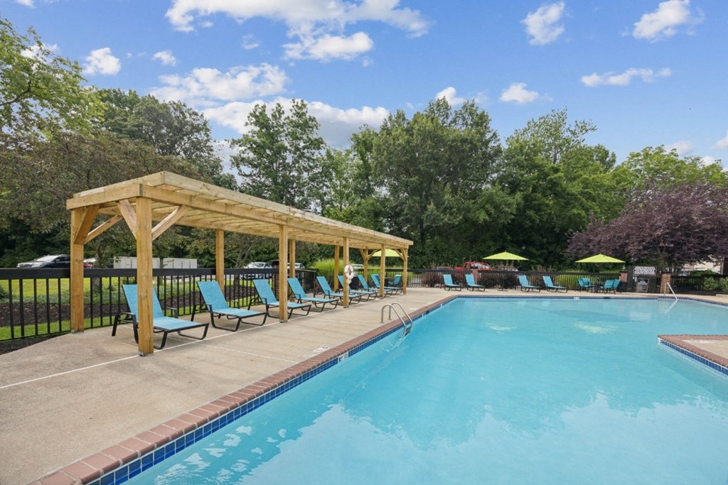 a swimming pool with blue chairs and a wooden pavilion next to it
