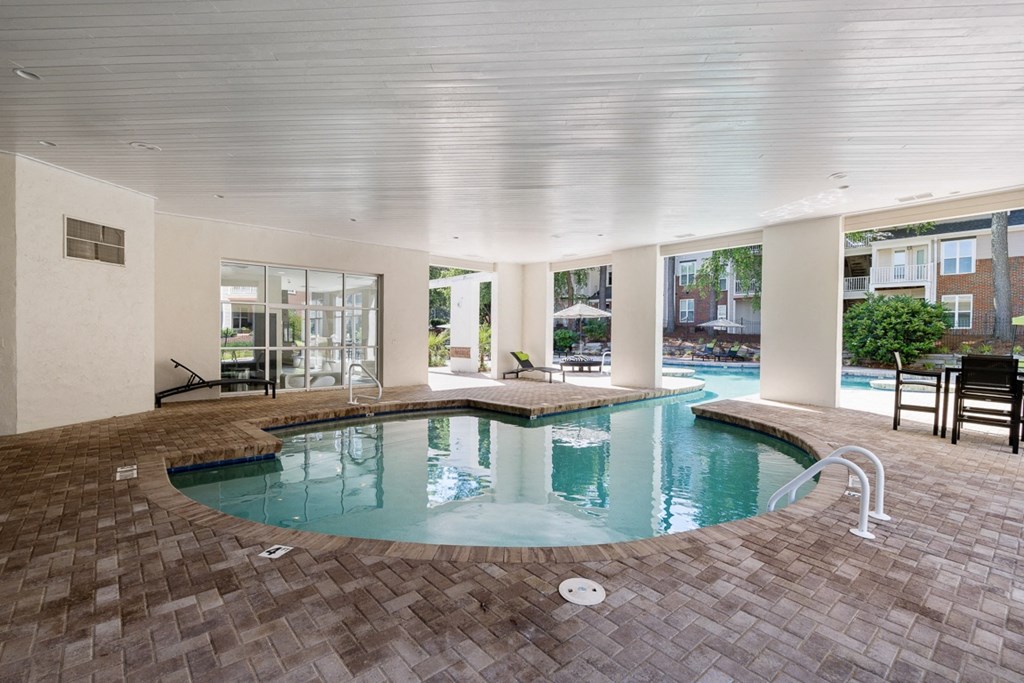 a large swimming pool with a spa in the middle of a room with glass doors at The Falls Apartments in Raleigh NC