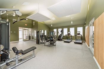 A gym with a variety of equipment including treadmills, weights, and exercise machines.