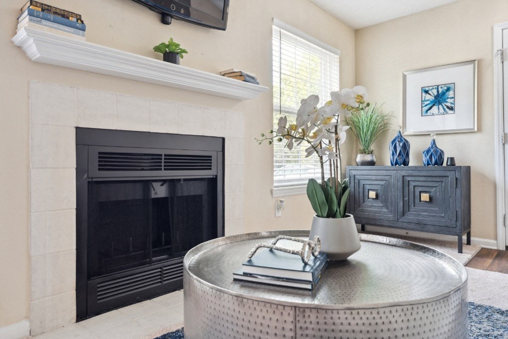 a living room with a fireplace and a table with a vase of flowers on it  at Willow Ridge Apartments, Charlotte, 28210