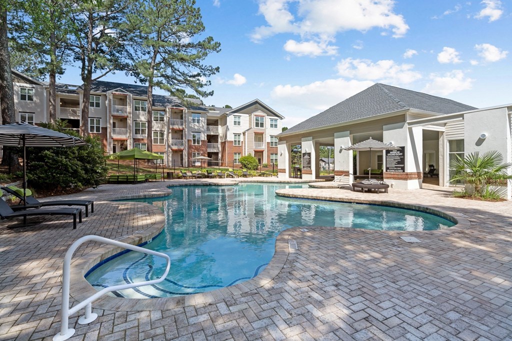 a swimming pool with an apartment building in the background at The Falls Apartments in Raleigh NC
