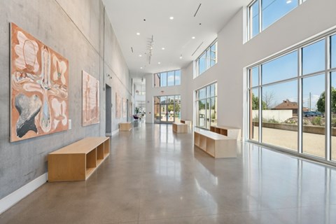 A spacious hallway with artwork on the walls and benches along the sides at South Falls Tower Apartments, Richmond