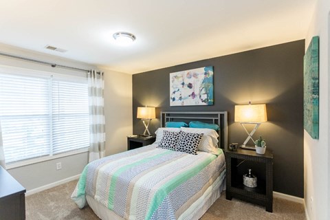 a bedroom with a bed and two night stands with lamps at The Resort At Lake Crossing Apartments, PRG Real Estate, Lexington, KY