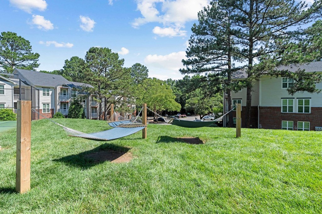 a yard with hammocks and houses in the background at The Falls Apartments in Raleigh NC
