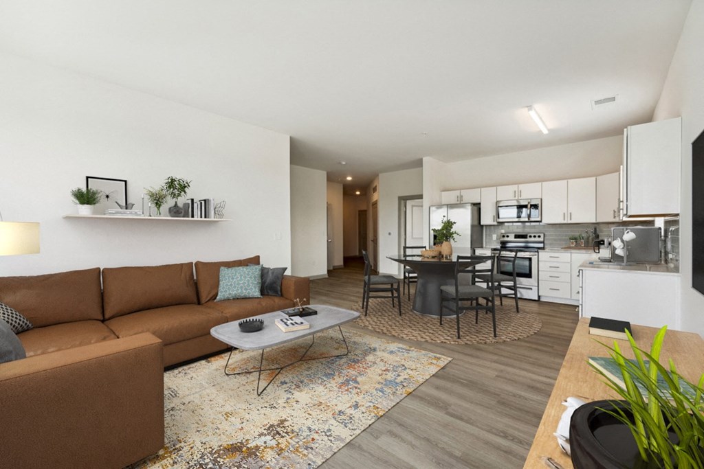 a living room with a couch a table and a chair and a kitchen in the background