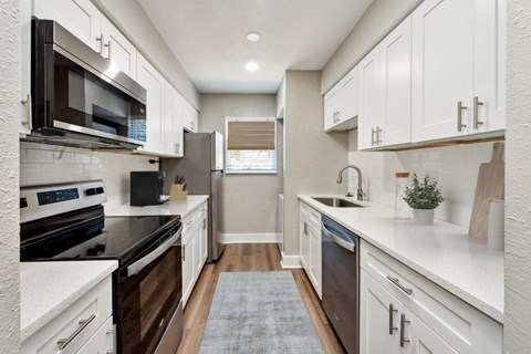 an open kitchen with white cabinets and black appliances