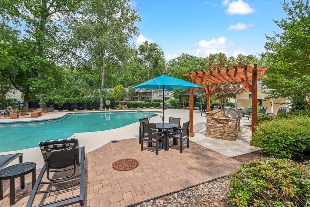 a backyard with a pool and patio with tables and umbrellas