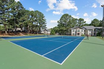 A tennis court with a green and blue surface at The Falls Apartments in Raleigh NC