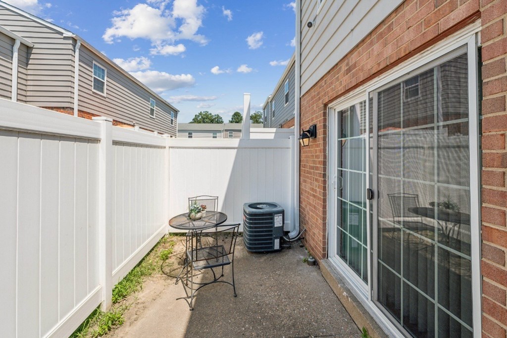 A patio with a table and chairs is surrounded by a white fence at Staples Mill Townhomes Apartments, Richmond, VA