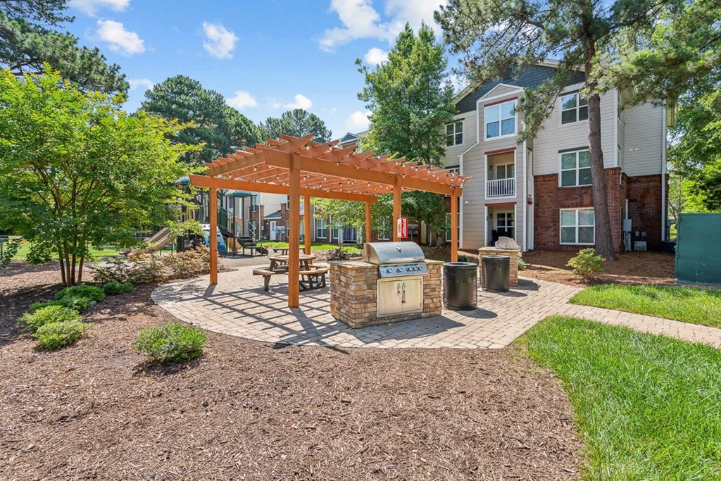 a patio with a picnic table and a grill at The Falls Apartments in Raleigh NC