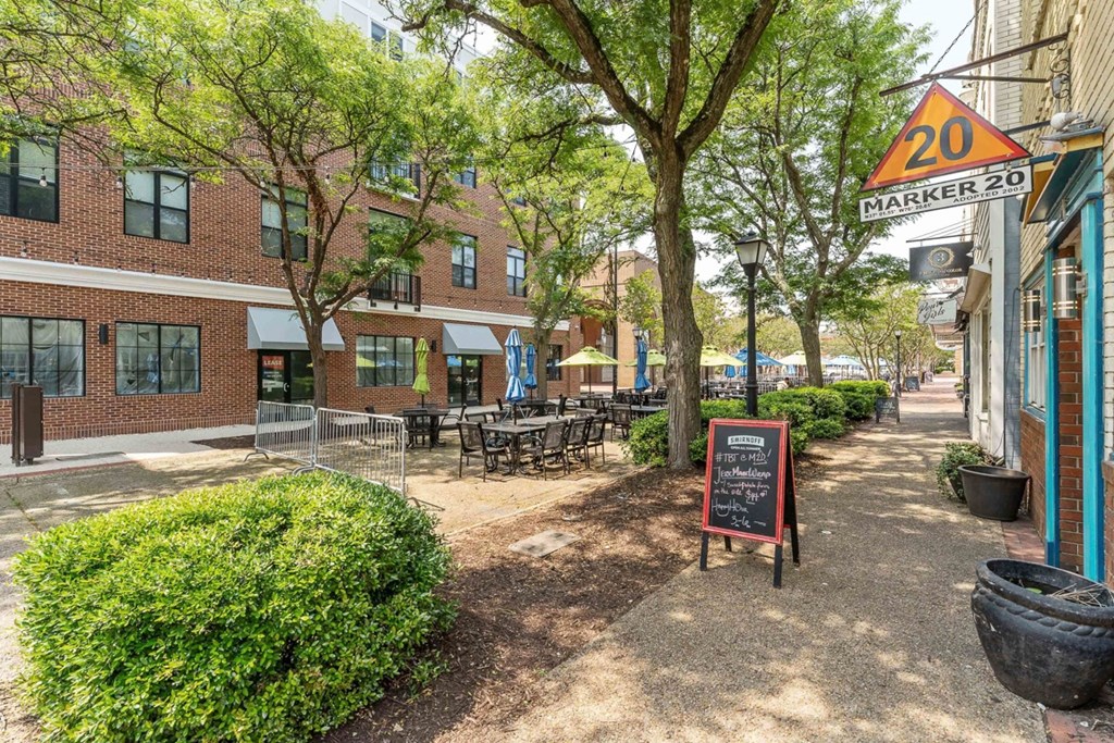 a sidewalk with tables and chairs in front of a brick building at The Constellation Apartments, PRG Real Estate, Hampton, Virginia
