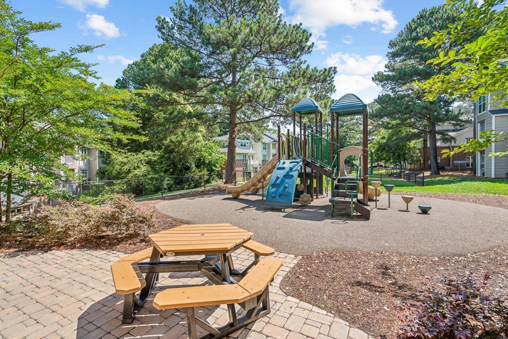 a playground with a slide and picnic tables at The Falls Apartments in Raleigh NC