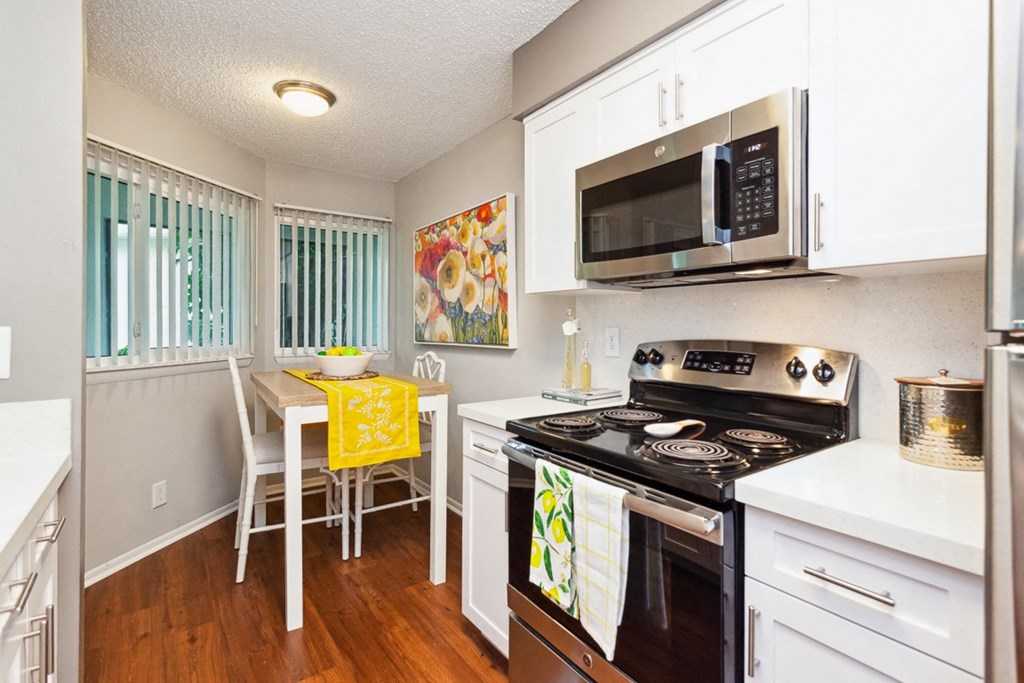 a kitchen with a stove and microwave and a table and chairs