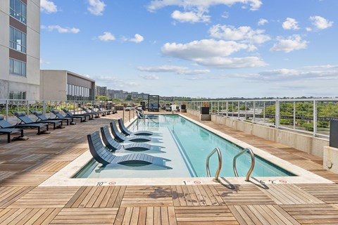 A large outdoor pool with wooden decking and lounge chairs at South Falls Tower Apartments, Richmond, VA