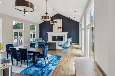 A modern dining room with a fireplace and blue chairs. at The Timbers Apartments, Richmond 23235
