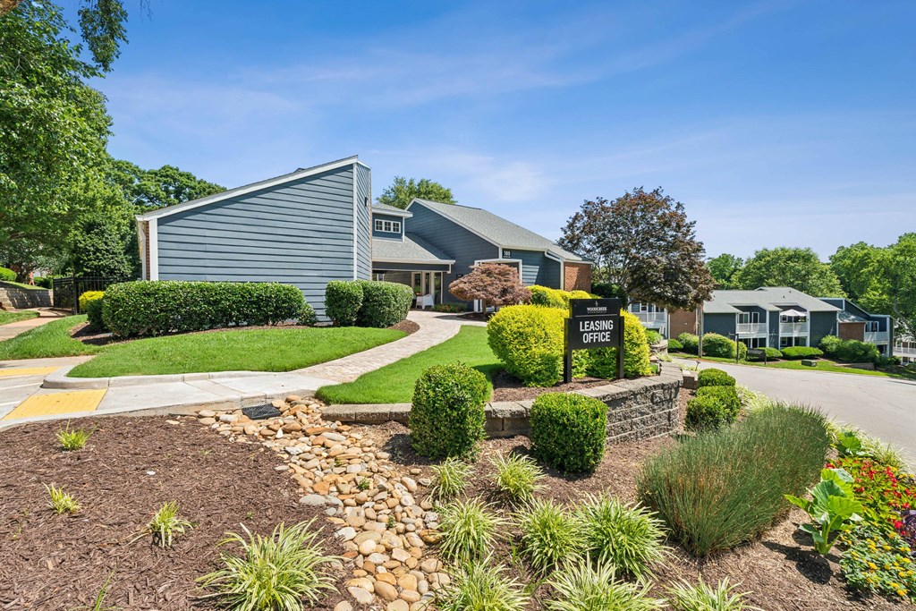 A well-maintained garden surrounds a building with a sign that reads  at Woodcreek Apartments, Cary, NC