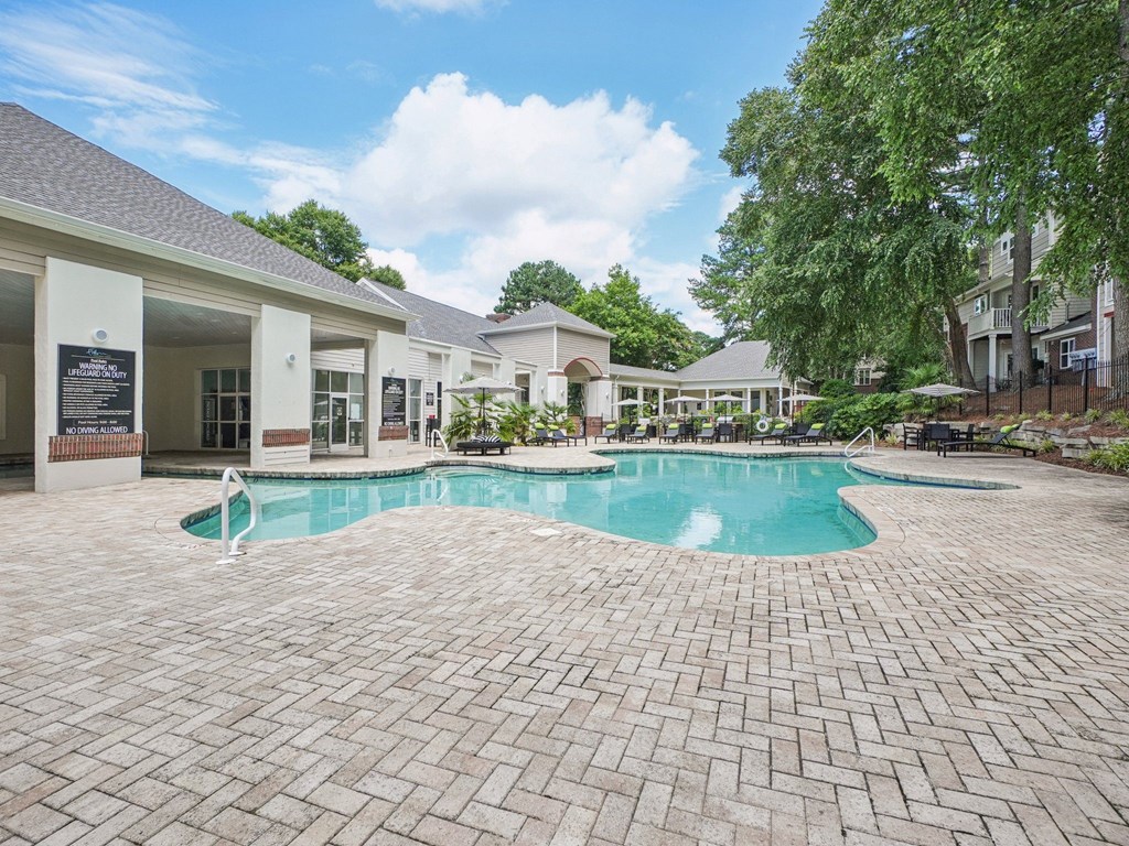 A large outdoor swimming pool surrounded by a brick patio at The Falls Apartments in Raleigh NC