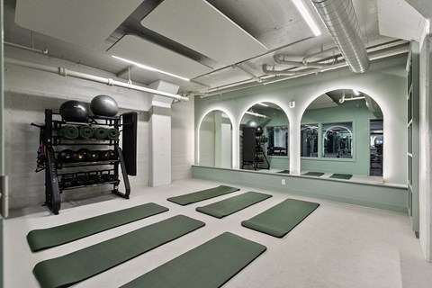 A gym with green mats and a weight rack at The Carousel Apartments, Virginia
