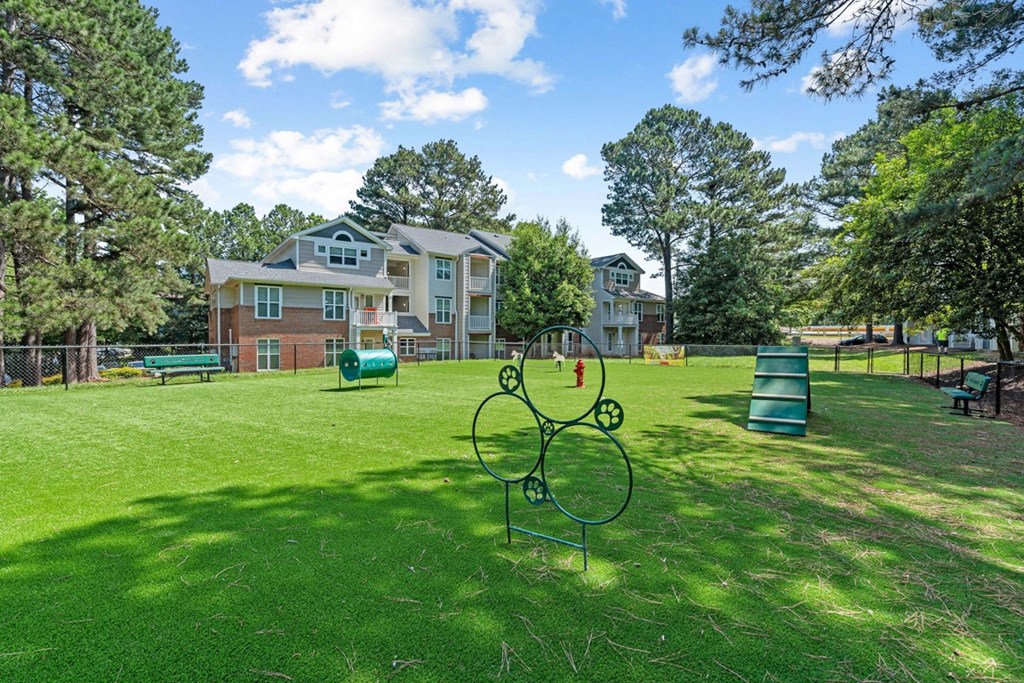 a park with a playground and houses in the background at The Falls Apartments in Raleigh NC