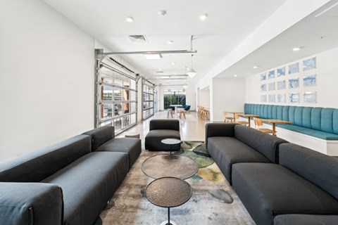 A modern living room with black sofas and a glass wall.