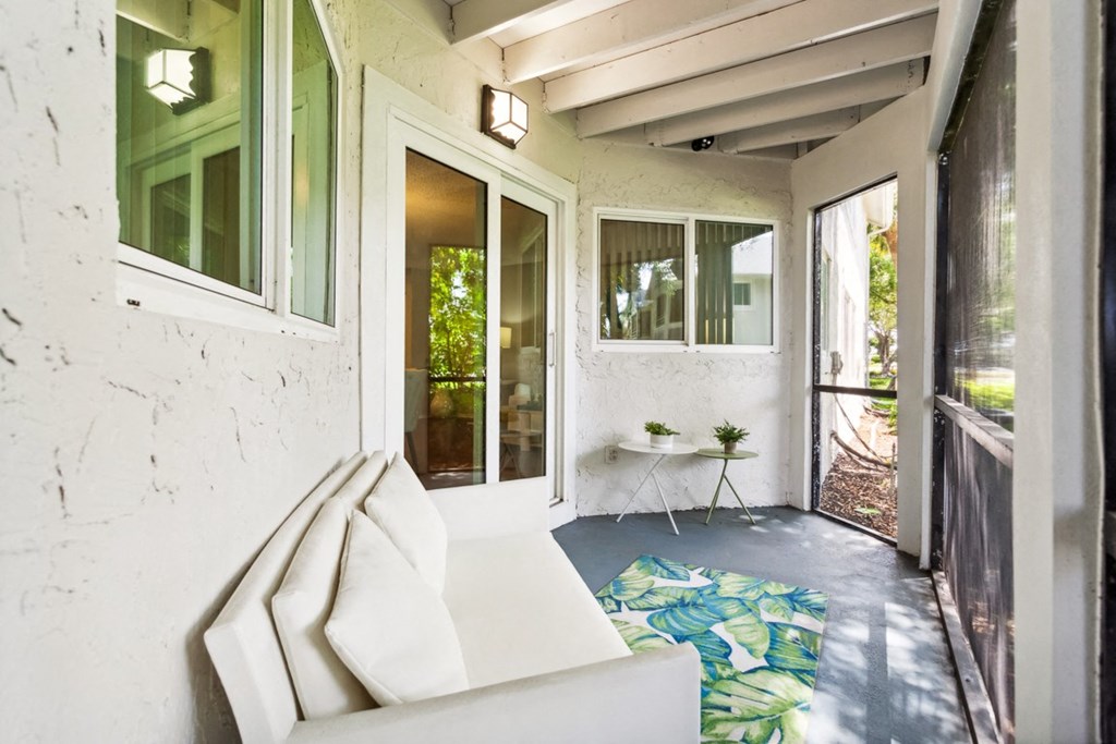 a porch with a white couch and a table on a rug