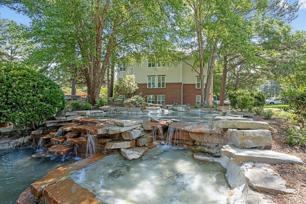 a backyard with a waterfall and rocks at The Falls Apartments in Raleigh NC