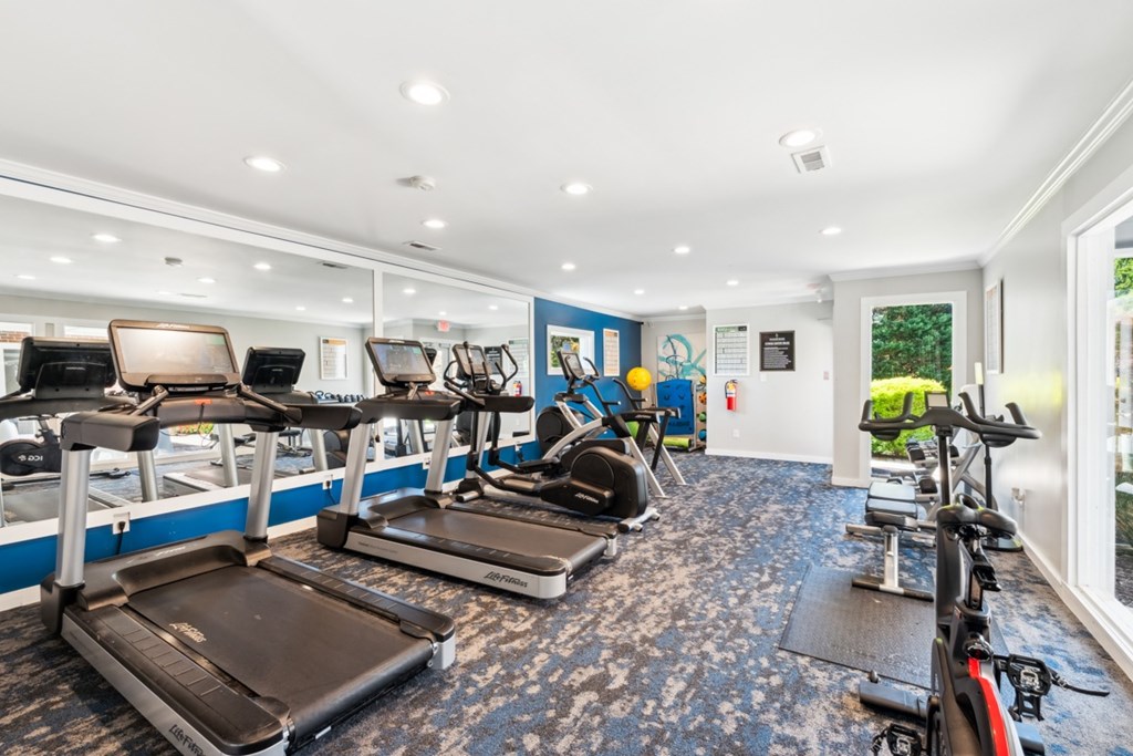 A gym with treadmills, exercise bikes, and elliptical machines. at Woodcreek Apartments, Cary 27511