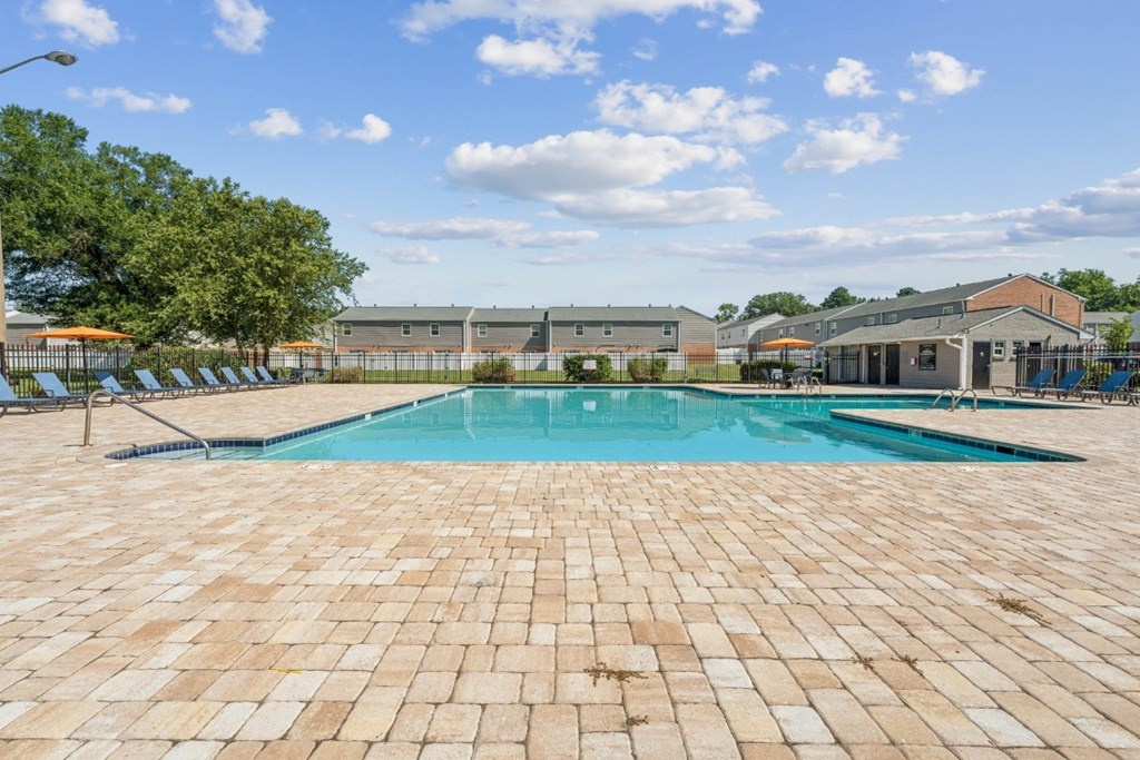 A large outdoor swimming pool surrounded by a brick patio at Staples Mill Townhomes Apartments, Richmond 23228