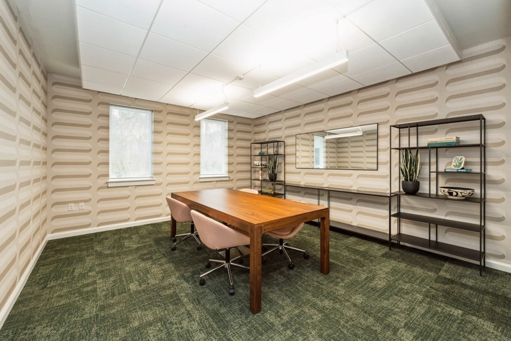 A room with a wooden table and chairs with a green carpet at The Courtyards of Chanticleer Apartments, Virginia Beach, Virginia