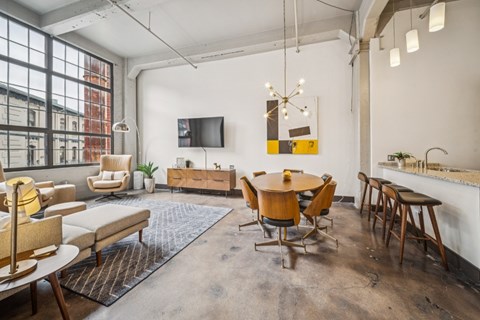 A modern living room with a large window, a flat screen TV, and a dining table with chairs.