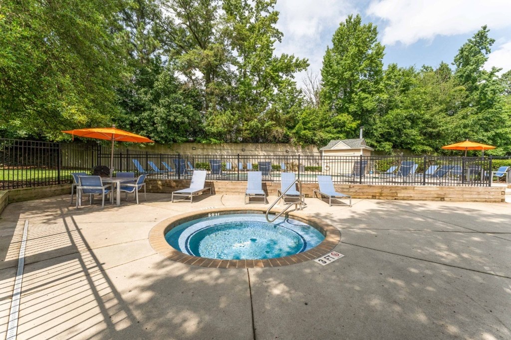 a hot tub with chaise lounge chairs and umbrellas  at Willow Ridge Apartments, Charlotte