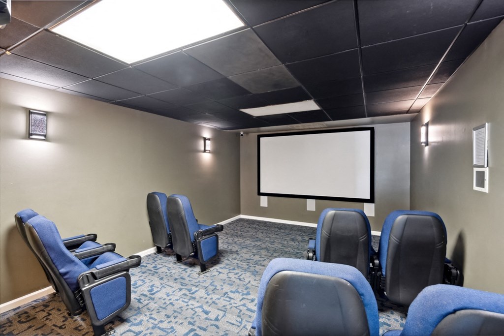a screening room with blue chairs and a projector screen at The Falls Apartments in Raleigh NC
