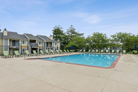 A swimming pool surrounded by lounge chairs and trees. at Chinoe Creek Apartments, Lexington, Kentucky