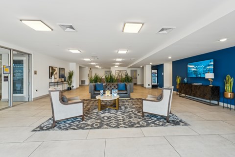 A spacious lobby with a blue accent wall and a large screen TV  at The Waterford At Rocketts Landing Apartments, PRG Real Estate, Richmond, Virginia