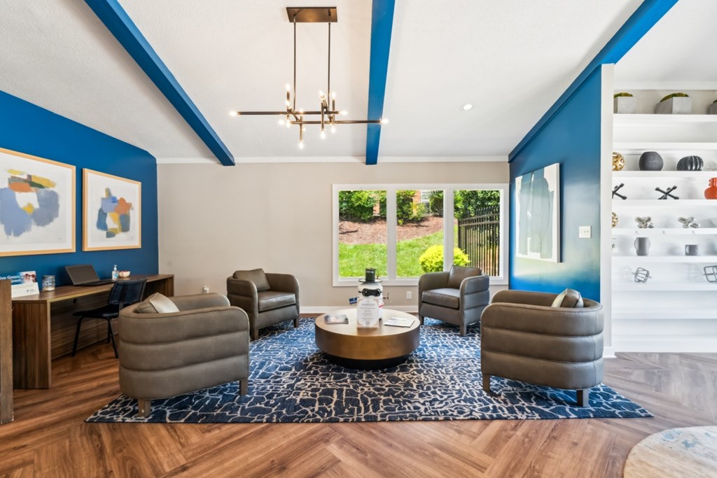 A living room with a blue accent wall and a large window at Woodcreek Apartments, Cary