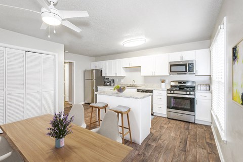 a kitchen and dining room with white cabinets and stainless steel appliances