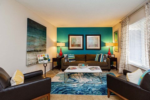 A living room with a brown leather couch, a coffee table, and a painting on the wall.