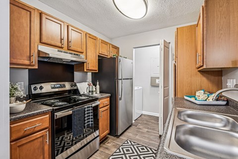 A kitchen with wooden cabinets and a black and white patterned rug.