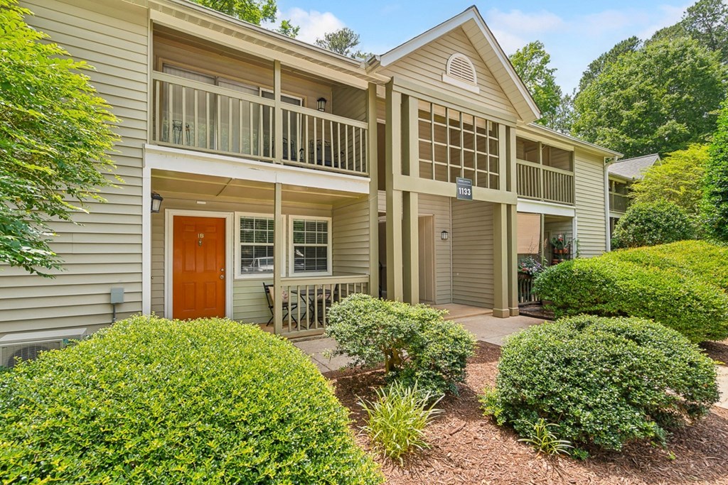 the front of a house with a porch and a red door
