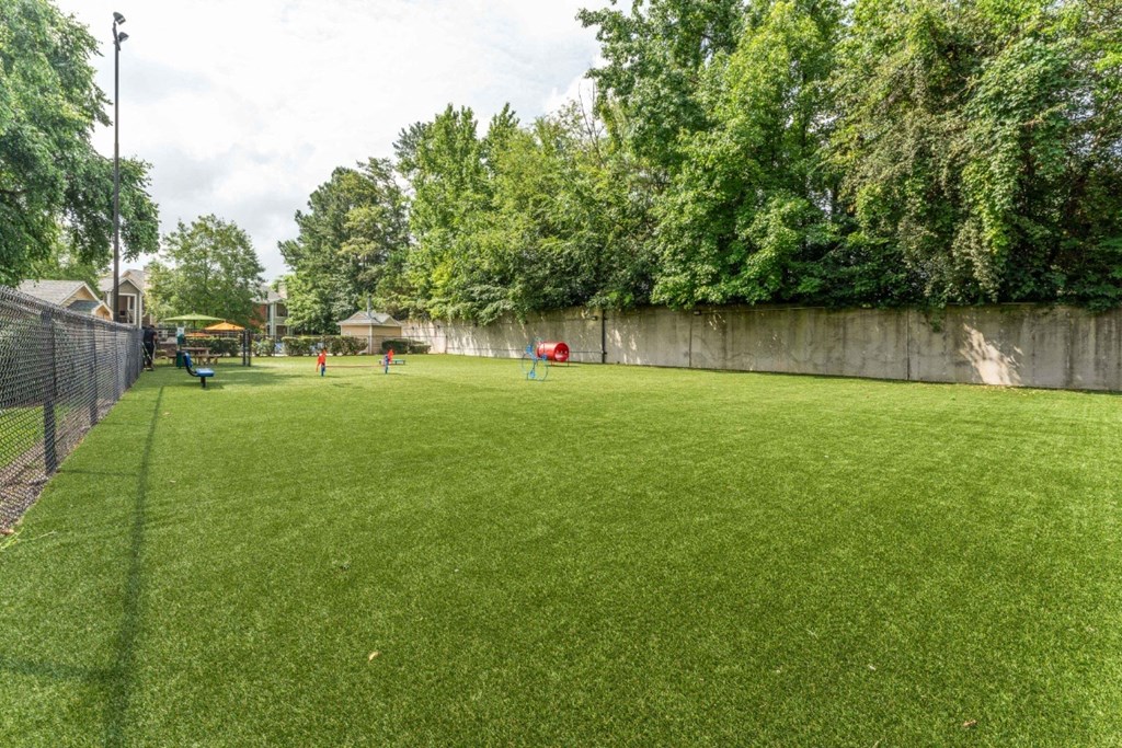 a large grassy area with a fence on one side and a playground on the other  at Willow Ridge Apartments, North Carolina