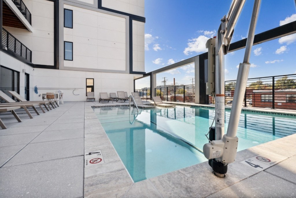 a pool with lounge chairs and a building in the background  at The Box, Virginia, 23224