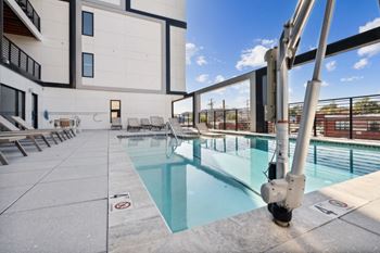 a pool with lounge chairs and a building in the background  at The Box, Richmond, VA