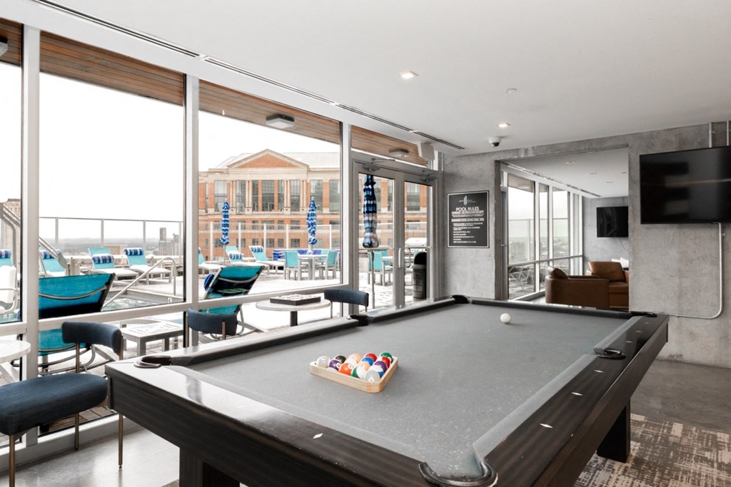 A pool table in a room with a view of the outside.