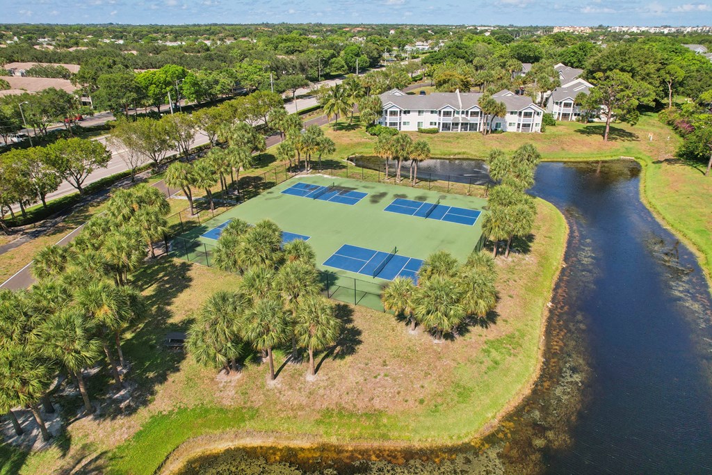 a tennis court with a house on the side of a lake