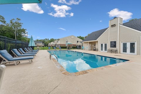 A pool with a blue umbrella and lounge chairs at Sawgrass Apartments, Charleston 29412