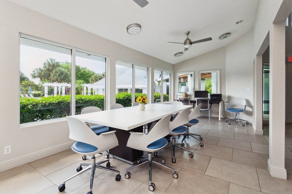 a conference room with a white table and chairs and windows
