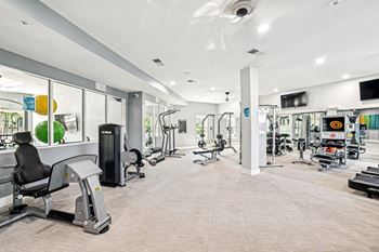 A gym with a variety of equipment including treadmills, weights, and exercise machines at Proximity Apartments, Charleston, SC