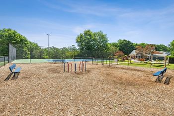 A playground with a swing set and a slide. at Woodcreek Apartments, Cary, NC, 27511