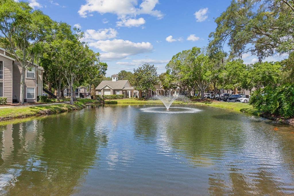 a fountain in the middle of a pond with houses on the other side  at Palm Crossing, Winter Garden